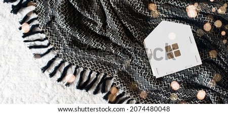 White toys house on black and white blanket with lights, top view, copy space, banner