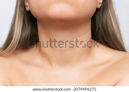 Сlose-up of a young woman's neck and collarbone on a white background. Lines on the neck. Wrinkles, age-related changes, rings of Venus, goosebumps. Skin care