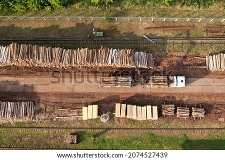 Timber truck unloading a cut trees in at woodworking plant. Transportation raw timber from felling site. Crane loads logs for lumber mill. Warehouse of lumber at woodworking factory. Royalty-Free Stock Photo #2074527439