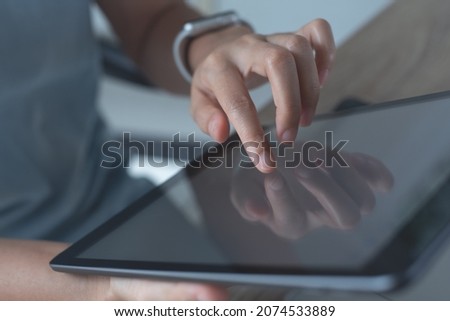 Woman hand holding, using digital tablet and touching on the screen, finger signing e-document or reading ebook via e-reader app, closeup, paperless office, business and technology concept