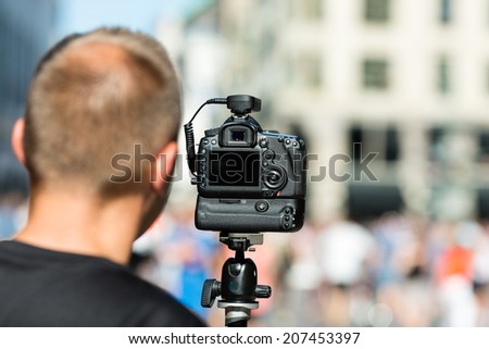 Male photographer preparing for photography assignment on a crowded street.