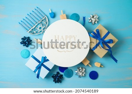 Hanukkah holiday greeting card with menorah, gift box and spinning top on blue background