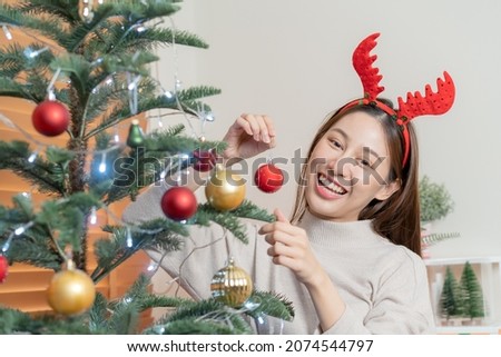 Decorating Christmas tree on season festival, beautiful asian young woman, girl holding red ball, bauble, happy to get present on merry xmas. Celebration decorations on New year day, holiday people.