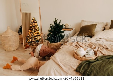 Funny kids brother and sister play hide-and-seek in a decorated bedroom in a cozy house on Christmas holiday. Selective focus