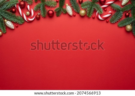 Red background. Copy space for Christmas creep. Border of fir branches, gifts, Christmas balls, and candy cane