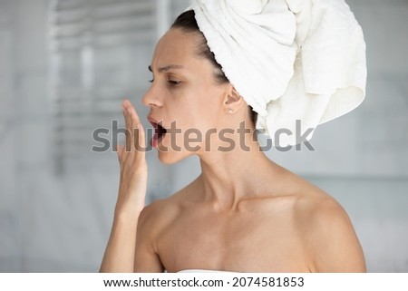 Stressed young hispanic latina woman holding hand near mouth, checking breath freshness, worrying about poor oral hygiene, suffering from unpleasant odor, having problems with caries gingivitis. Royalty-Free Stock Photo #2074581853