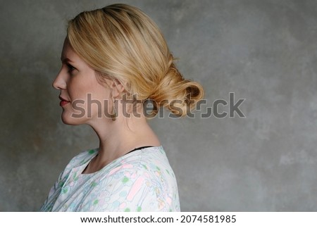 beautiful blonde woman turned her face aside into the darkness, creating intrigue. shabby wall background