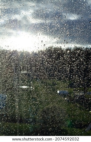 Drops of rainwater through the window and a view of nature behind the window.