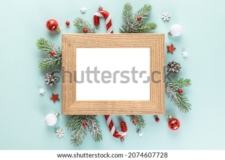 Christmas or Happy New Year photo frame with fir tree branches, holiday decorations on blue background. Flat lay. Mock up. Top view
