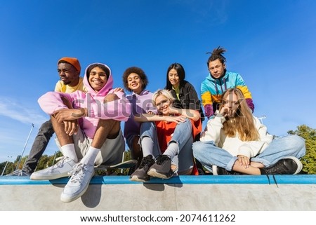Multicultural group of young friends bonding outdoors and having fun - Stylish cool teens gathering at urban skate park Royalty-Free Stock Photo #2074611262