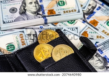 Close up of metal shiny bitcoin crypto currency coins in a leather wallet on US dollar bills. Electronic decentralized money concept.