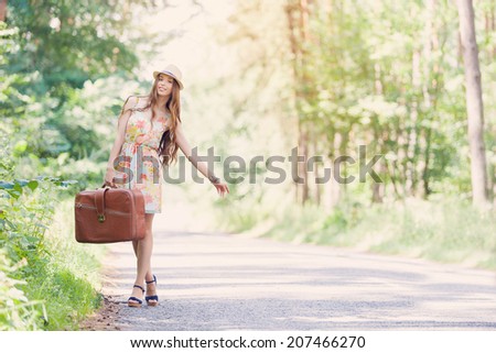 happy young girl with vintage camera and valise walking outdoors in the park