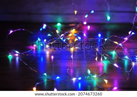 Photo of a New Year's garland, sparkling with colorful lights. During the winter holidays, it is customary to decorate houses with bright lights. The subject is photographed in close-up.