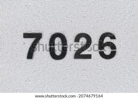 Black Number 7026 on the white wall. Spray paint. Number seven thousand twenty six.
