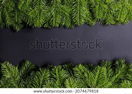 Black paper background with green fir tree branches frame with copy space for text