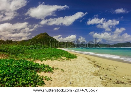 serangan beach. Panorama of Indonesia's tropical beaches with green grass, white sand, hills, clouds and blue skies and clear water.