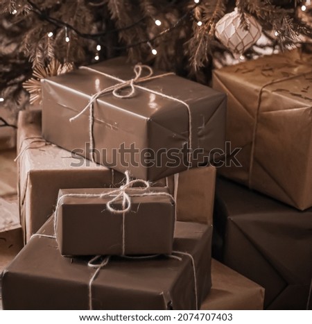 Christmas holiday delivery and sustainable gifts concept. Brown gift boxes wrapped in eco-friendly packaging with recycled paper under decorated xmas tree.