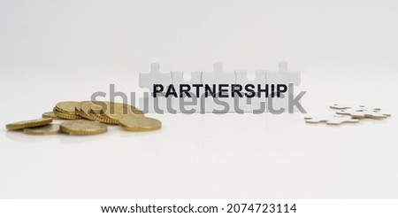 Business and finance. On a white background, there are coins and puzzles with the inscription - PARTNERSHIP