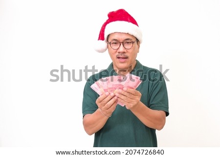 Man in green t-shirt and Santa's hat counting some money, ready for Christmas 2022 shopping