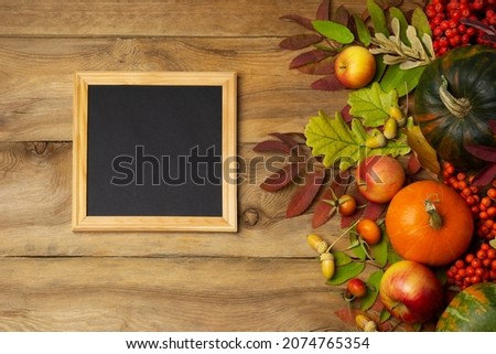 Wooden square picture frame mockup with rosehip, pumpkins and fall leaves. Empty frame mock up for presentation design. Template framing for modern art.