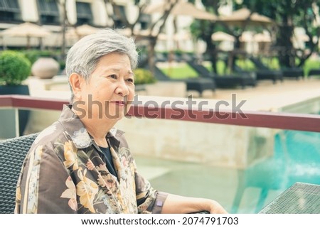 asian elder female woman resting relaxing on balcony terrace at hotel resort. elderly senior leisure lifestyle