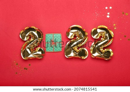 Balloons in shape of figure 2022 and cookie on color background