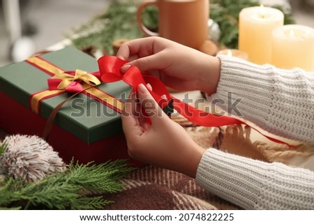 Woman decorating Christmas gift box at table