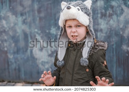 Child in a wolf hat on gray background, outdoor. High quality photo
