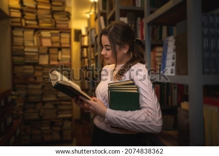 beautiful cute young girl reads and studies in the local library. Library concept. Reading concept