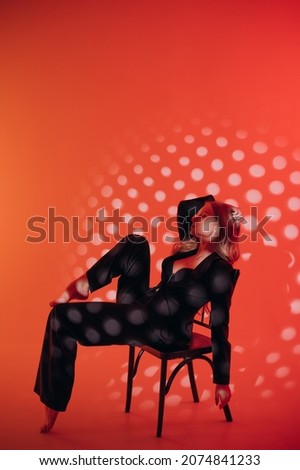 beautiful girl in black suit, blonde hair, red background, photo studio