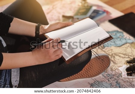 A woman sitting on a map and making a travel plan