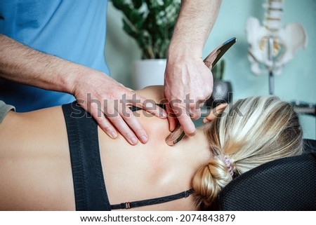 IASTM mysofacial Release For Rhomboid And Back Pain Using Smart Tools, Therapist using IASTM instrument to treat scapular pain Royalty-Free Stock Photo #2074843879