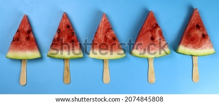watermelon popsicle on a stick on a blue background flat lay. Horizontal banner