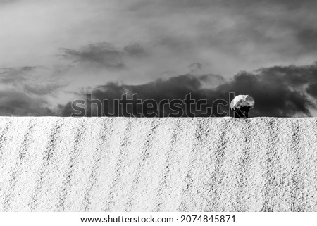 large roof of a house with a small chimney covered with snow against a gray cloudy sky black and white photo