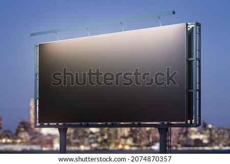 Blank black billboard on cityscape background at evening, perspective view. Mock up, advertising concept