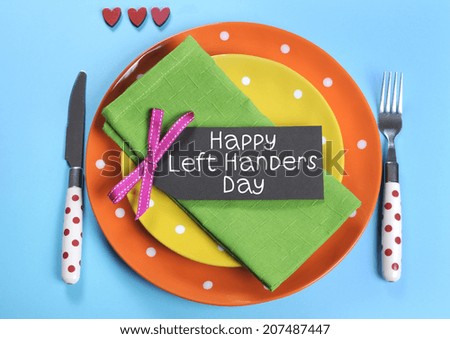 Happy Lefthanders Day, for August 13, International Left-handers Day, with colorful table setting showing reverse cutlery placing, in orange, yellow, pale blue and green polka dot colors. Royalty-Free Stock Photo #207487447