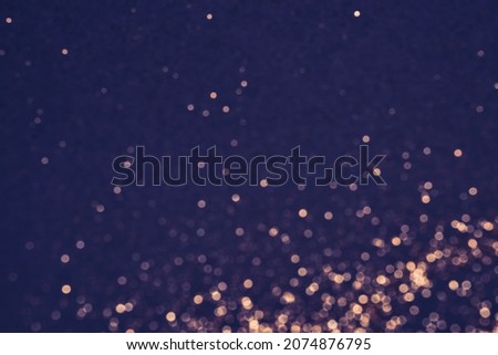 Purple festive background of golden glitter lights. Winter blurred abstraction