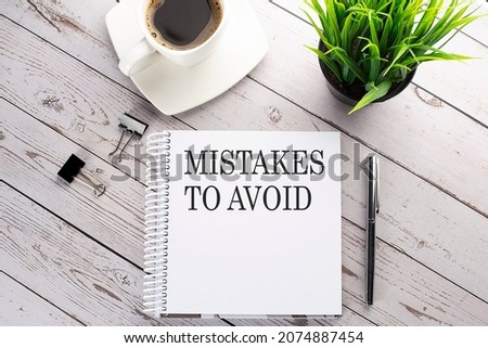 Cofee cup, notepad,pen on wooden background. Business concept. Text MISTAKES TO AVOID Royalty-Free Stock Photo #2074887454