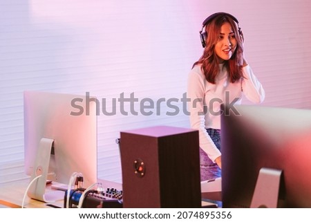 Asian female vocalist wearing headphones and standing in the studio in a rehearsal session. Performance and show in the music business. Image with copy space. focus on a female.