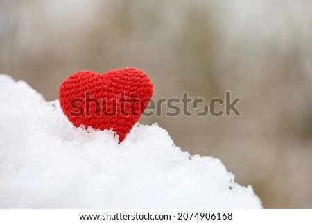 Love heart in the snow in winter park. Valentine's card, red knitted symbol of love, background for romantic event, Christmas celebration