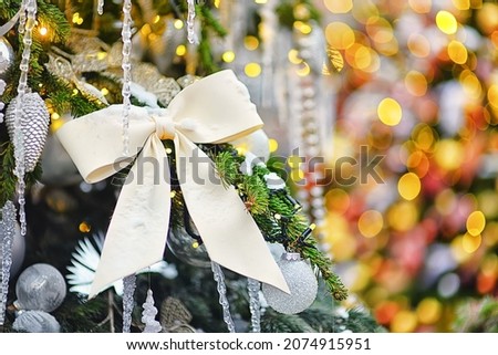 White New Year's bow on a beautiful Christmas tree. New Year's decorations
