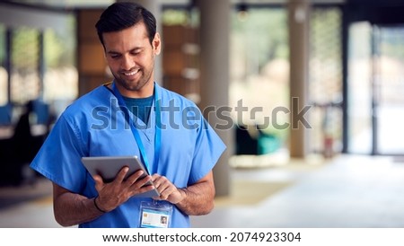 Male Medical Worker In Scrubs With Digital Tablet In Hospital