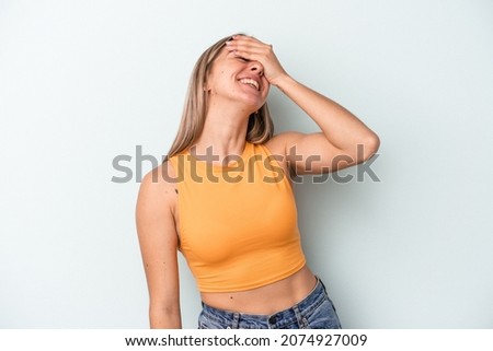 Young caucasian woman isolated on blue background laughs joyfully keeping hands on head. Happiness concept.