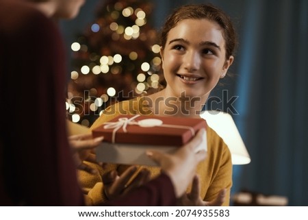 Happy girl receiving a beautiful Christmas gift from her mother