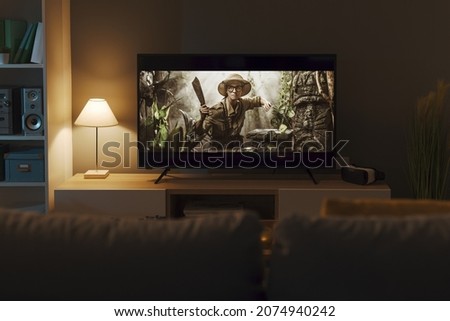 Exciting adventure movie on a widescreen TV and living room interior Royalty-Free Stock Photo #2074940242