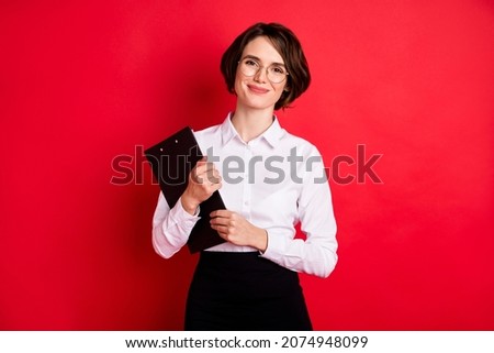 Photo of happy positive lovely charming secretary in glasses hold organizer smiling isolated on red color background Royalty-Free Stock Photo #2074948099