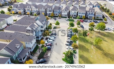 Aerial view row of townhome cottage style houses near community park with public art installation near historic Old Town Coppell, Texas, USA. Upscale houses with no backyard, beautiful fall foliage Royalty-Free Stock Photo #2074961062