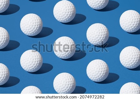 Arranged white golf ball on blue pastel background. Minimal design.