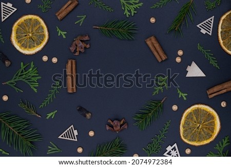Happy new year, christmas wreath made of pine branches, toys and bright oranges with cinnamon on black background, flat lay top view