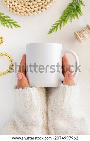 Close up White Coffee cug Mockup. Feminine hands holds ceramic mug. Flat lay bordered withfir branch and xmas decorations Royalty-Free Stock Photo #2074997962